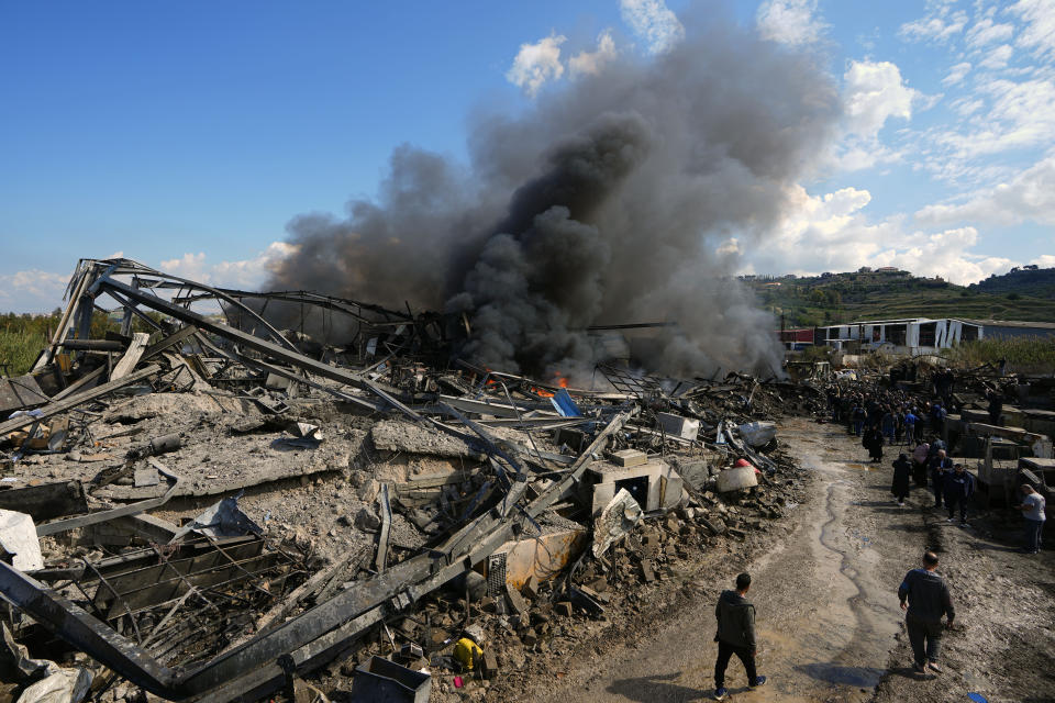 People gather at a destroyed warehouse that was attacked on Monday by Israeli airstrikes, at an industrial district in the southern coastal town of Ghazieh, Lebanon, Tuesday, Feb. 20, 2024. Israeli warplanes carried out at least two strikes near the southern port city of Sidon in one of the largest attacks near a major city, wounding a dozen of people, Lebanese state media said. (AP Photo/Bilal Hussein)