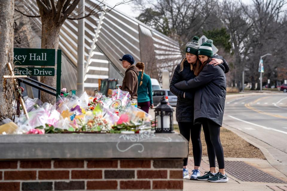 Women look over memorials outside of Berkey Hall on the Michigan State University campus in East Lansing on Monday, Feb. 21, 2023, as classes resumed following the mass shooting at the university that partially took place in the building.