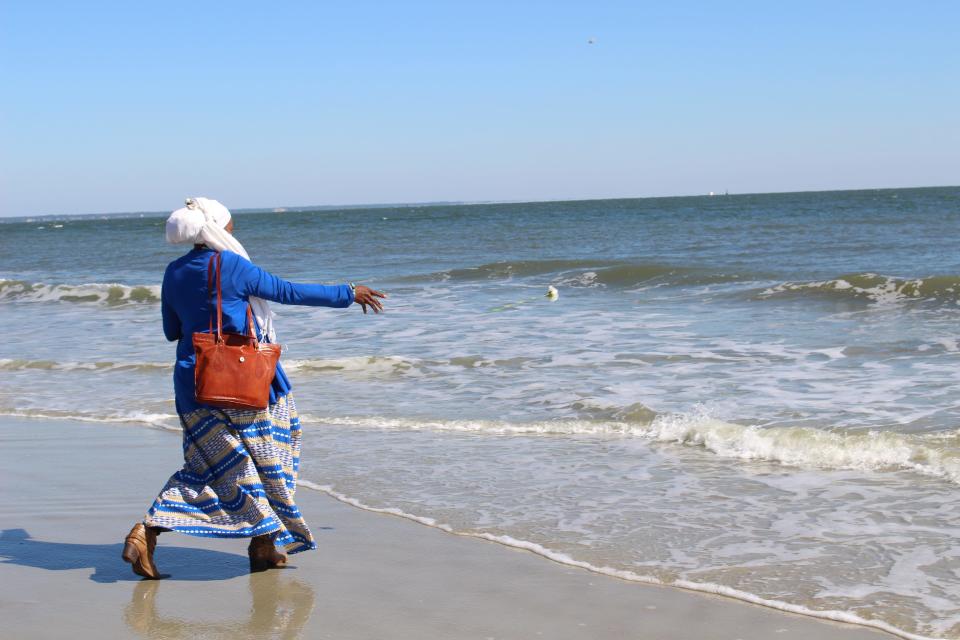 Attendees of Tybee's Remembrance Ceremony, including Sakinah Ziyadah'Ali, throw a white carnation into the ocean to commemorate the captive Africans who were brought to Tybee's shores.