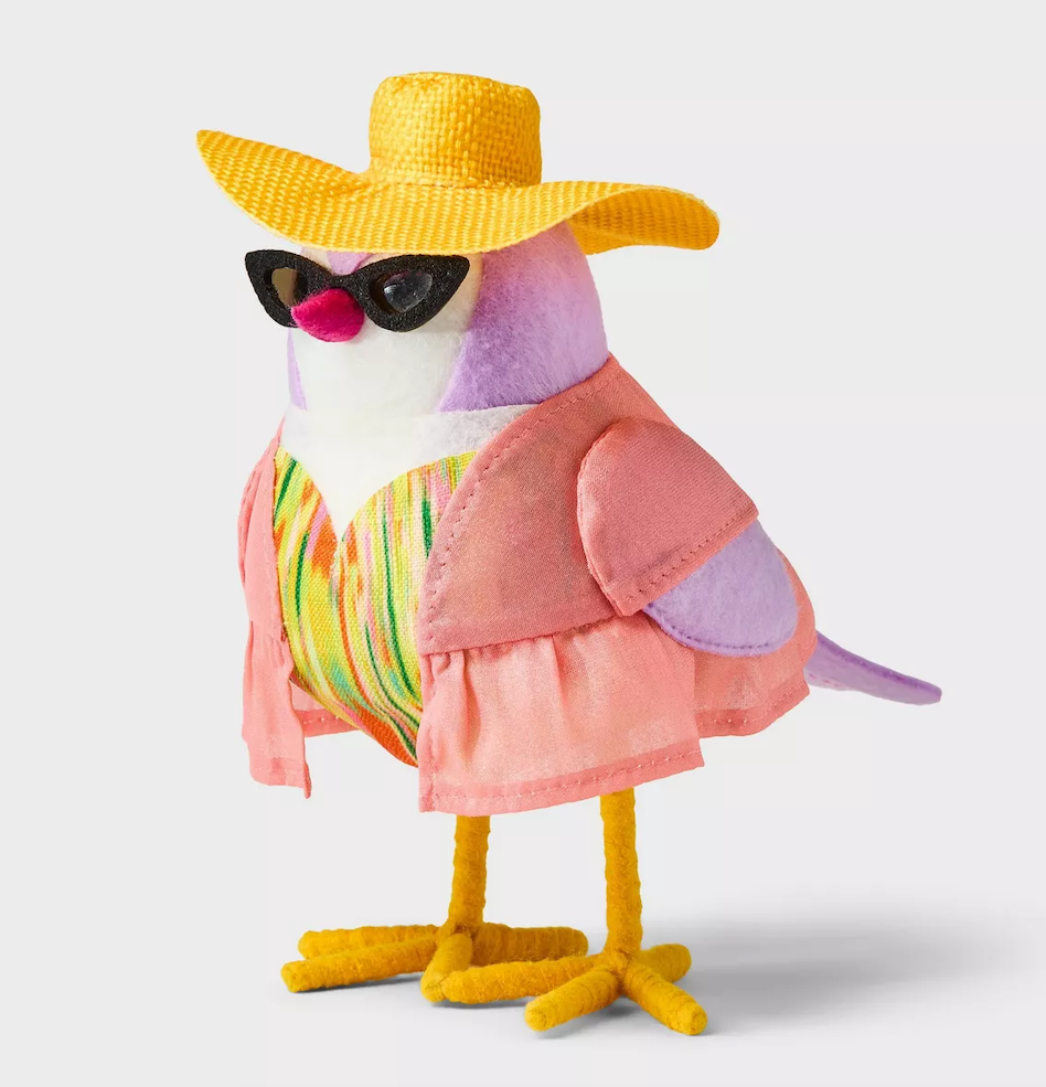 Bird doll dressed in summer-themed clothing, including a yellow hat, sunglasses, a pink shirt, and a colorful striped top