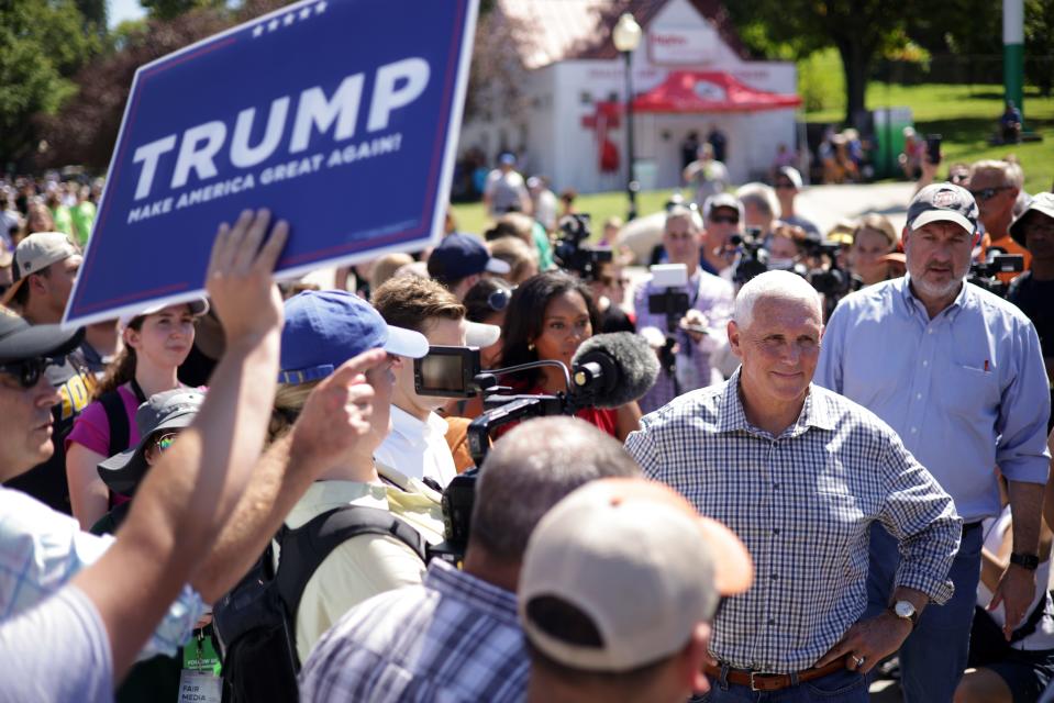 Republican presidential candidate and former Vice President Mike Pence speaks to members of the press as a Trump supporter holds up a Trump campaign sign at the Iowa State Fair on August 11, 2023 in Des Moines, Iowa.