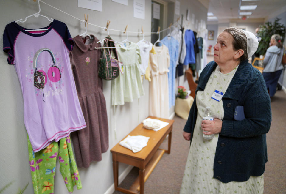 Darlene Shirk observa una muestra de ropa que lucían víctimas de abusos sexuales menores de edad en las comunidades amish, menonitas y otras en un seminario sobre prevención del abuso infantil en Leola (Pensilvania) el 29 de abril del 2022. (AP Photo/Jessie Wardarski)