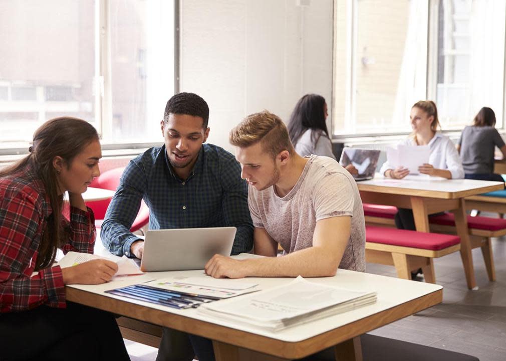 A group of college students using a laptop and having a discussion.