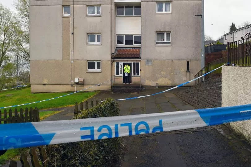 An officer standing guard at a block of flats amid the probe into the killing of Jack Trainner.