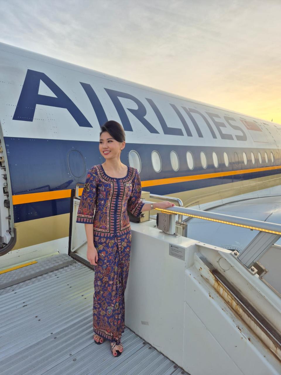 A flight attendant stands in front of a Singapore Airlines plane.