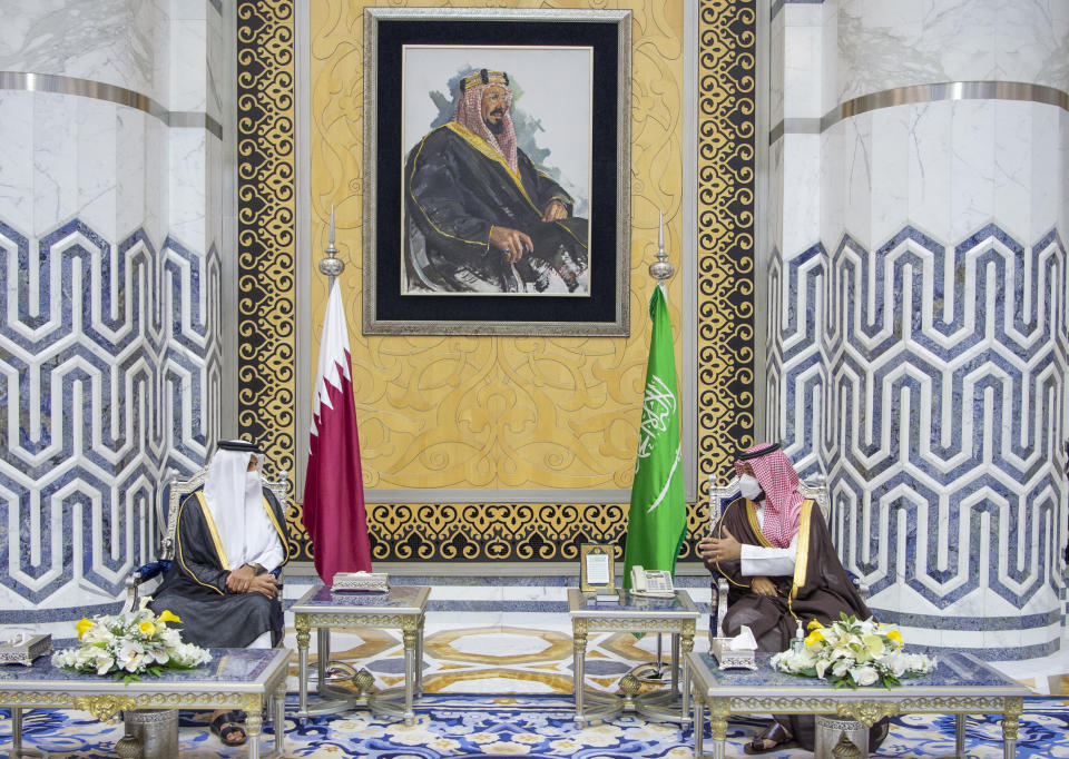 In this photo released by Saudi Royal Palace, Saudi Crown Prince Mohammed bin Salman, right, meets with Qatar's Emir Sheikh Tamim bin Hamad Al Thani in the Red Sea city of Jiddah, Saudi Arabia, Monday, May 10, 2021. Qatar's ruling emir is visiting Saudi Arabia for the first time since signing a declaration with other Arab Gulf states to ease a years-long rift and end an embargo that had frayed ties among important U.S. allies and security partners. At top a framed photo shows Saudi Arabia's founder, the late King Abdul Aziz Al Saud. (Bandar Aljaloud/Saudi Royal Palace via AP)
