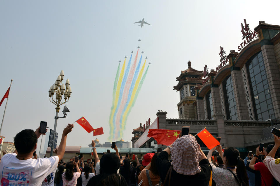 People hold their mobile phones and Chinese flags as military aircraft fly in formation during the military parade marking the 70th founding anniversary of People's Republic of China, at a railway station in Beijing, China October 1, 2019. (Photo: Tingshu Wang/Reuters)