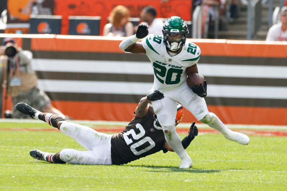 New York Jets running back Breece Hall (20) tries to break away from Browns cornerback Greg Newsome II during the second half, Sunday, Sept. 18, 2022, in Cleveland.