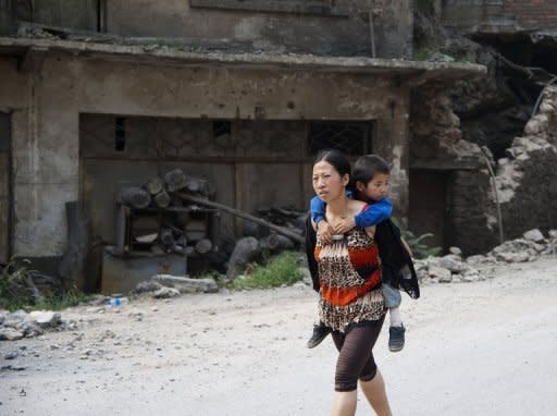 A woman carries her child in Yiliang on September 8 after two quakes hit the border of southwest China on Friday. Some residents have left for nearby shelters, but most had departed before the ambulances, army vehicles and Red Cross jeeps arrived on the scene