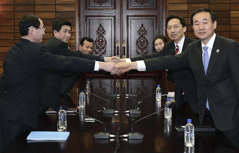 In this photo released by South Korean Unification Ministry, head of South Korean working-level delegation Lee Duk-haeng, center right, shakes hands with his North Korean counterpart Park Yong Il, center left, during their meeting at Tongilgak in the North Korean side of Panmunjom which has separated the two Koreas since the Korean War, Wednesday, Feb. 5, 2014. Red Cross delegates from the rival Koreas begun talks Wednesday on holding reunions of families separated since the Korean War ended in the early 1950s. (AP Photo/South Korean Unification Ministry)