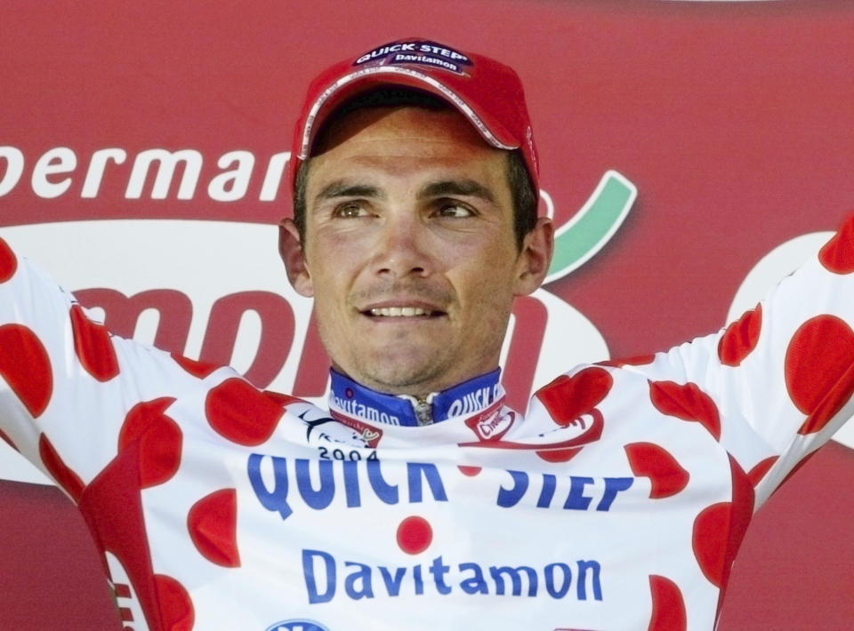 FILE - In this Wednesday, July 14, 2004 file photo, Richard Virenque of France, who took over the best climber's dotted jersey, celebrates on the podium after winning the 10th stage of the Tour de France cycling race between Limoges and Saint-Flour, central France. A 700-kilogram Salers cow was the gigantic prize rewarding Frenchman Richard Virenque for his stage win on Bastille Day in 2004 in the town of Saint-Flour, where the start of stage 10 will be given on Monday July 15, 2019. (AP Photo/Laurent Rebours, File)