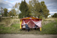 Members of an election commission sit in a tent as they wait for voters at a mobile polling station during the Parliamentary elections in Rogachevo village, Moscow region, Russia, Saturday, Sept. 18, 2021. The Communist Party and independent observers have reported an array of alleged violations in the voting that is widely expected to keep the dominant United Russia party's majority in parliament. (Evgeny Feldman/Meduza via AP)