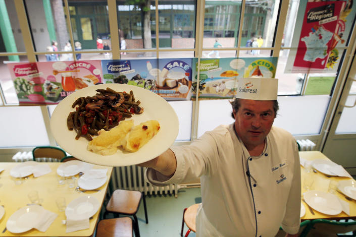 French chef Xavier Lebeau poses with a plate of Quenelles de Brochet (pike fish) with Green Haricots and Champignons de Paris (Paris mushrooms) at the Saint Pierre de Chaillot school in Paris, Tuesday, May 6, 2014. In France, school lunch is an art form: hot, multi-course and involving vegetables. (AP Photo/Francois Mori)