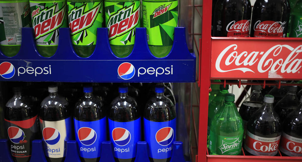 Bottles of Pepsi and Mountain Dew soda for sale next to Coca-Cola Co. brand beverages.