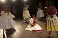 En esta imagen del 30 de abril de 2019, miembros de la compañía de teatro "Kory Warmis", o Mujeres e oro bailan en torno a Erika Andia, directora del grupo, que actúa con una pieza de atrezzo en brazos que representa a un bebé recién nacido en la obra "Kusisita" en el Teatro Municipal de La Paz, Bolivia. (AP Foto/Juan Karita)