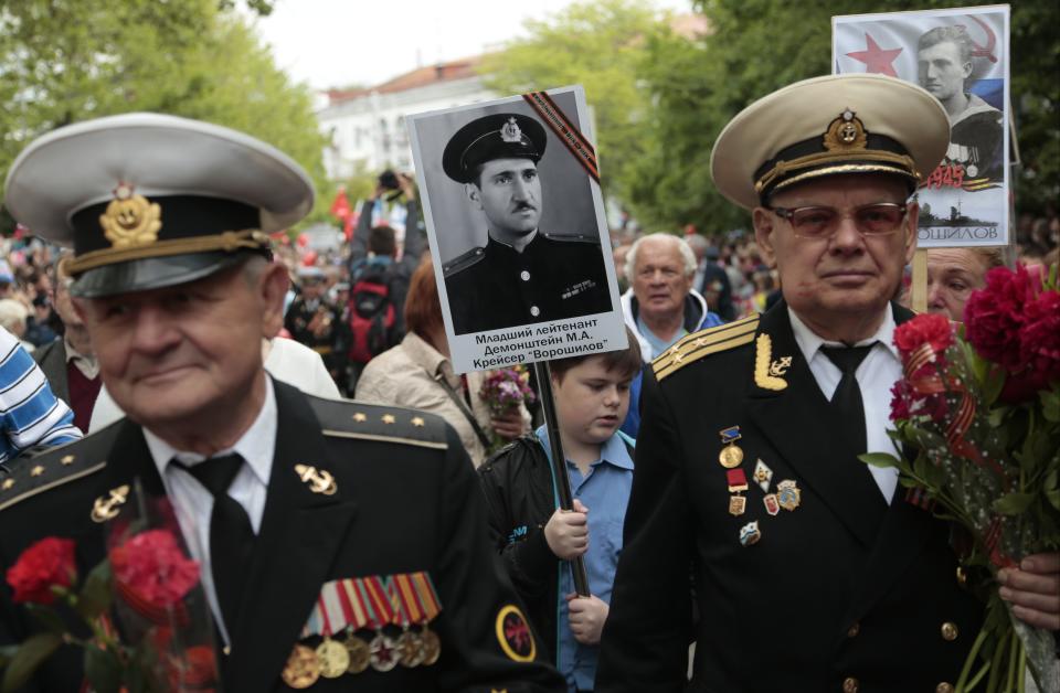 A boy carries a portrait which reads "Lt. M.Demonshtein, Cruiser Voroshilov" during a Victory Day military parade in Sevastopol, Crimea, Friday, May 9, 2014. Crimea, which hosts a major Russian Black Sea Fleet base, is also set to hold a massive navy parade in the port of Sevastopol, celebrating the Russian takeover. (AP Photo/Ivan Sekretarev)