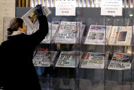 A customer takes a copy of a newspaper headlining Prince Harry and Meghan’s explosive TV interview at a newspaper stand outside a shop in London, Tuesday, March 9, 2021. Britain's royal family is absorbing the tremors from a sensational television interview by Prince Harry and the Duchess of Sussex, in which the couple said they encountered racist attitudes and a lack of support that drove Meghan to thoughts of suicide. (AP Photo/Frank Augstein)