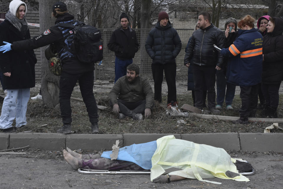FILE - People react standing near the body of a resident, killed in Russia's massive air attack in Zaporizhzhia, Ukraine, Friday, Dec. 29, 2023. The United Nations said in a new report Tuesday, Jan. 16, 2024, Russia’s intense missile and drone attacks across Ukraine in recent weeks sharply increased civilian casualties in December, with over 100 killed and nearly 500 injured. (AP Photo/Andriy Andriyenko, File)