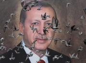 FILE PHOTO: Pigeons fly in front of a large poster of Turkish President Tayyip Erdogan in Bursa