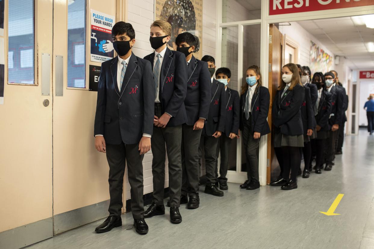 Year eight pupils wear face masks as a precaution against the transmission of the novel coronavirus as they queue in a corridor before attending an English lesson at Moor End Academy in Huddersfield, northern England on September 11, 2020. - Millions of children across England have returned to school after the Covid-19 lockdown with many schools introducing measures to enable as safe an environment as possible. (Photo by OLI SCARFF / AFP) (Photo by OLI SCARFF/AFP via Getty Images)