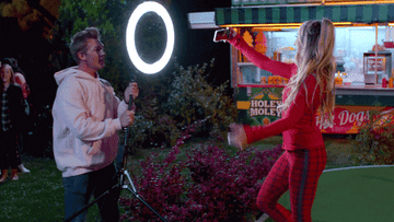 man moving a ring light for a woman taking a selfie