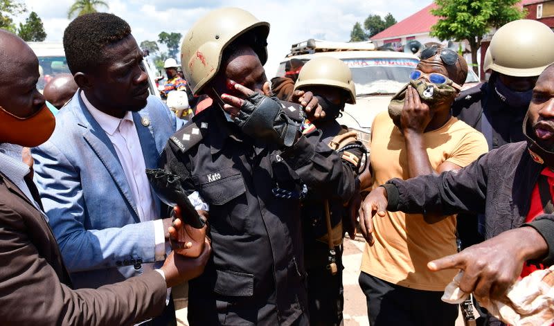 Ugandan pop star and presidential candidate Bobi Wine assists one of his bodyguards who was injured in clashes near Kampala