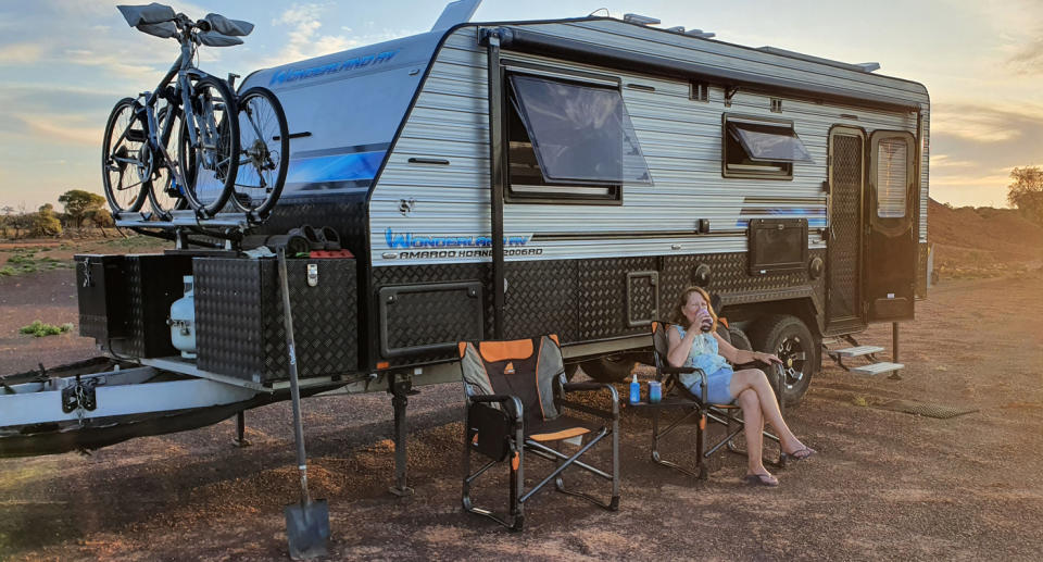 Leoni sitting on a camping chair in front of a caravan in Central Australia. 