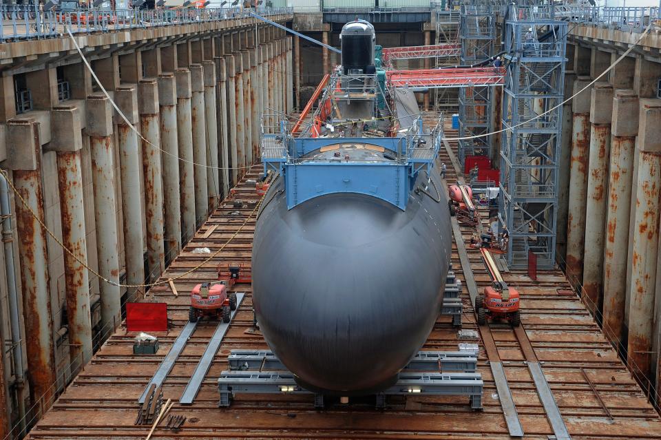 In this July 30, 2015, file photo, shipyard workers work at General Dynamics Electric Boat in Groton, Conn., prepare a submarine for float-off.