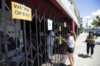 A woman pays for photo prints from George's Camera during curbside service Tuesday, May 19, 2020, in San Diego. With encouraging results in their fight against the coronavirus, San Diego County supervisors voted Tuesday to ask the state to allow California's second-largest county to be a test case for whether more rapid reopening can safely occur.(AP Photo/Gregory Bull)