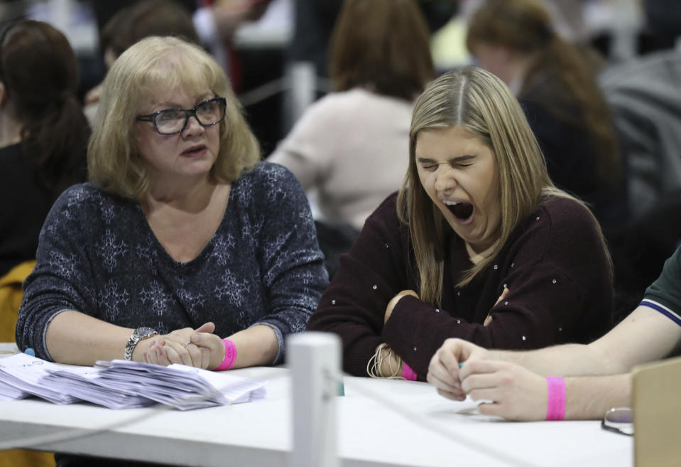 A member of the counting staff yawns as ballot papers are counted at the SEC Centre in Glasgow, Scotland Friday Dec. 13, 2019. An exit poll in Britain’s election projects that Prime Minister Boris Johnson’s Conservative Party likely will win a majority of seats in Parliament. That outcome would allow Johnson to fulfil his plan to take the U.K. out of the European Union next month. (Andrew Milligan/PA via AP)