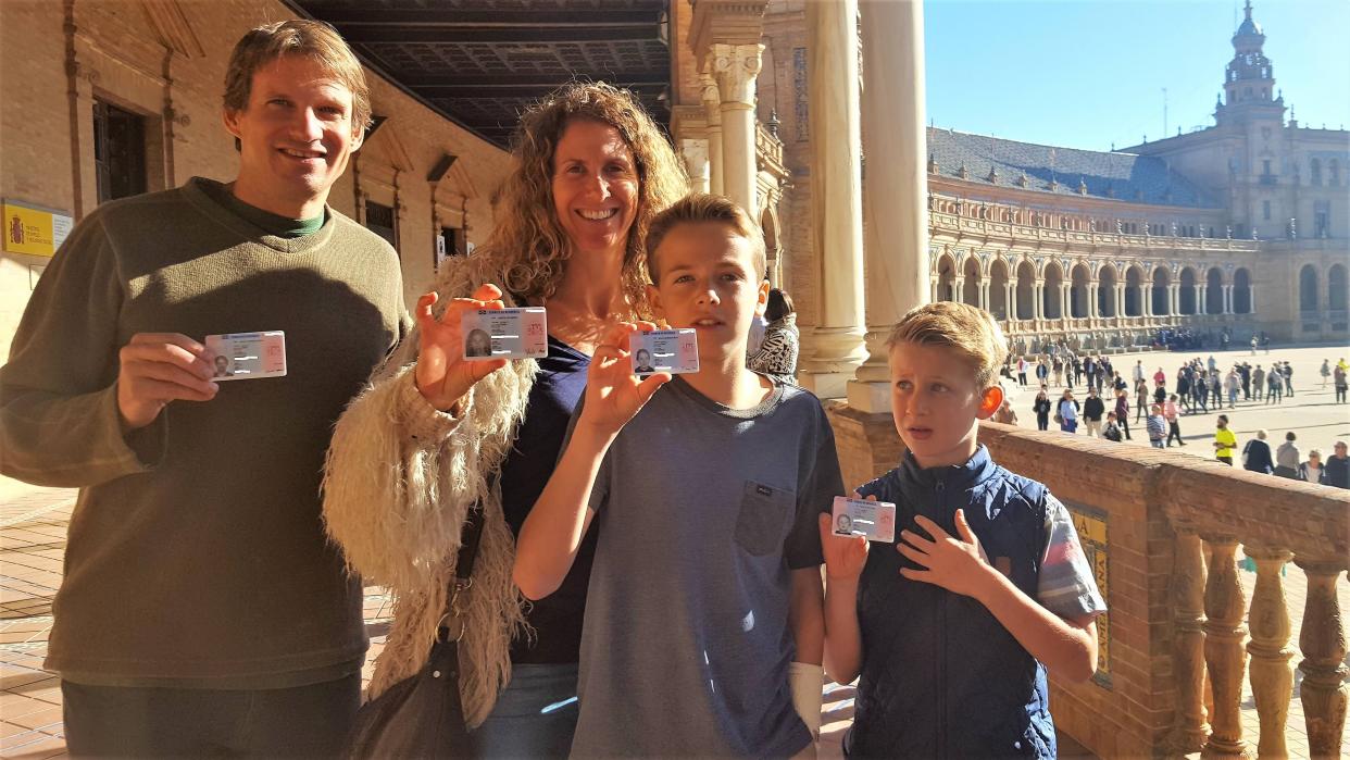 A family with two young sons posing with their foreigner's identity card at Real Alcazar of Seville.