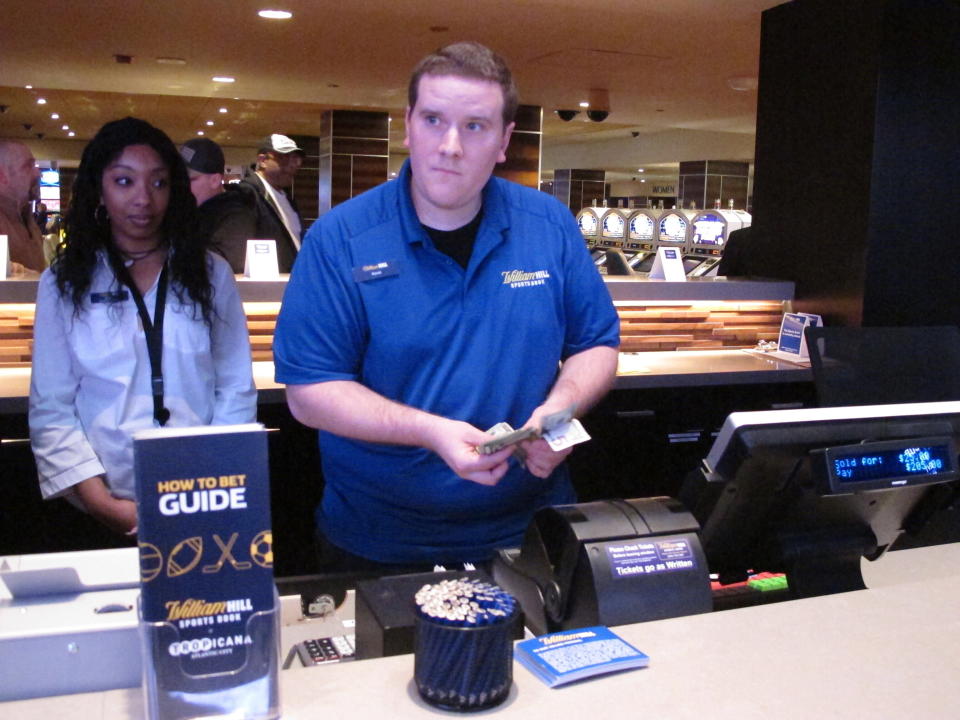 In this March 8, 2019 photo, a clerk counts money wagered by a customer at the sports betting lounge at the Tropicana casino in Atlantic City N.J. On Sept. 14, 2020, New Jersey gambling regulators announced that New Jersey set a new national record for the amount wagered on sports in a single month in the U.S. with nearly $668 million bet on games. (AP Photo/Wayne Parry)