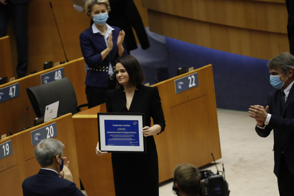 Belarusian opposition politician Sviatlana Tsikhanouskaya, center, is applauded as holds her prize during the Sakharov Prize ceremony at the European Parliament in Brussels, Wednesday, Dec. 16, 2020. The European Union has awarded its top human rights prize to the Belarusian democratic opposition. (AP Photo/Francisco Seco)