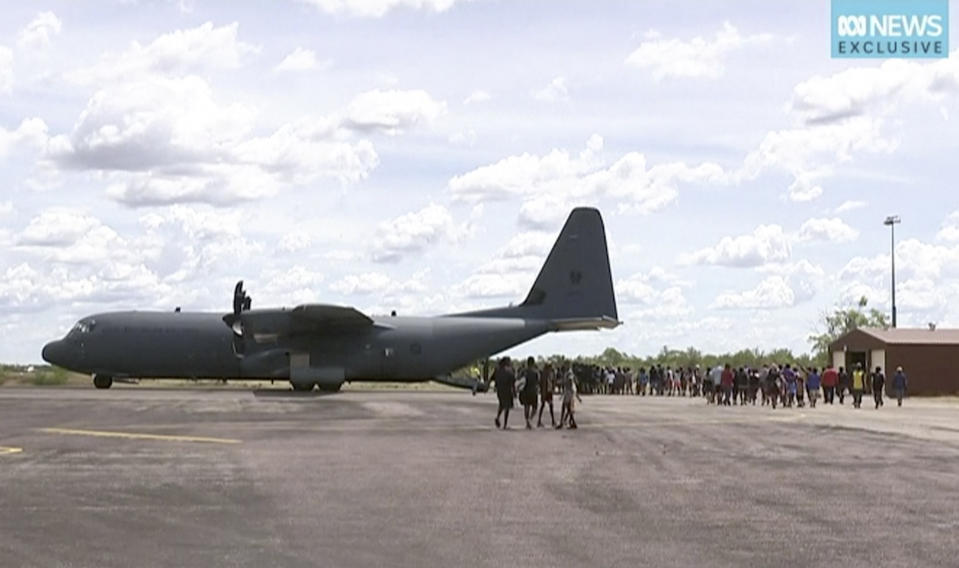 In this image made from video taken on March 21, 2019, storm evacuees board an Australian Defence Force C-130 plane preparing to take off from Borroloola, Australia. Two powerful cyclones are spinning toward Australia's sparsely populated north where around 2,000 people have been evacuated from the east coast of the Northern Territory ahead of strong winds, mountainous waves and flooding rain. (Australian Broadcasting Corporation via AP)