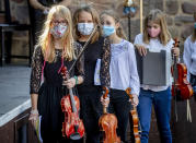 Young violinists wear face masks on the way to their music school concert in the old castle in Bad Vilbel near Frankfurt, Germany, Sunday, Sept. 20, 2020. (AP Photo/Michael Probst)