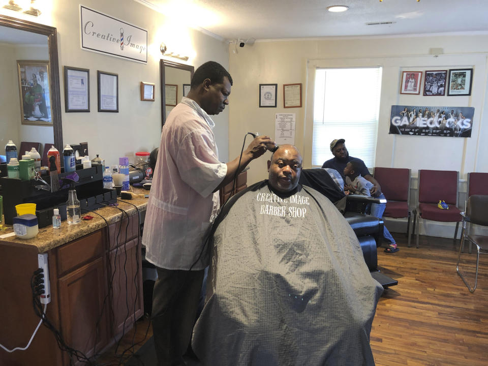 In this March 26, 2020, Patrick Goodman cuts Keith Donaldson's hair at Creative Image barber shop in Columbia, SC. South Carolina's governor has not given a stay at home order closing non-essential businesses, but Columbia did pass an order, which will close Goodman's shop. (AP Photo /Jeffrey Collins).