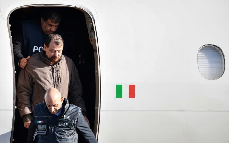 An Italian-flagged Falcon 900 plane carrying Battisti landed at Rome's Ciampino airport on Monday morning. Battisti, who was not wearing handcuffs, smiled grimly as he was escorted off the plane by a dozen police