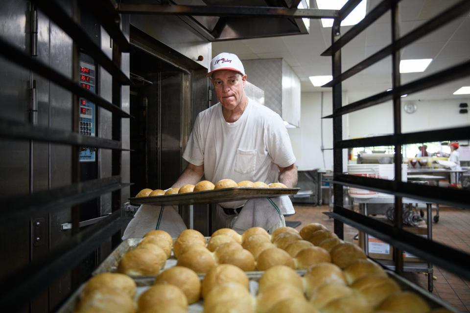 Nick Poulos pulls rolls out of an oven at Superior Bakery on Wednesday, April 19, 2023.