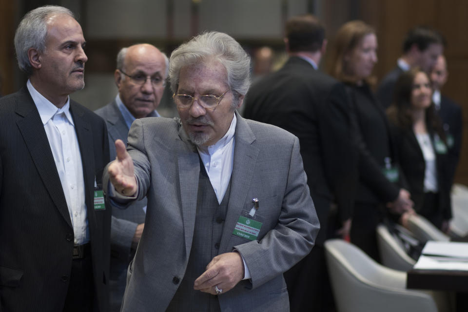 Mohsen Mohebi, agent for the Islamic Republic of Iran, gestures to his delegation to take their seats, as the U.S. delegation is seen in the background, as they wait for judges to enter the International Court of Justice, or World Court, in The Hague, Netherlands, Wednesday, Feb. 13, 2019. The court is scheduled to deliver its judgement on U.S. objections about the court's jurisdiction in the case. (AP Photo/Peter Dejong). (AP Photo/Peter Dejong)