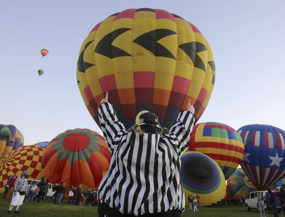 A Zebra or launch director gives the thumbs up to a balloonist for lift-off at the Albuquerque International Balloon Fiesta in Albuquerque, N.M., Sunday, Oct. 6, 2019. (Jerry Larson/Waco Tribune-Herald via AP)