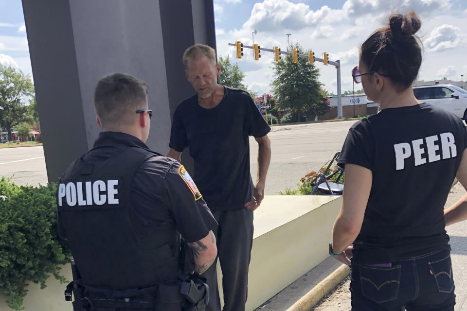 Chesterfield Patrol Officer Travis Adams, left, and peer recovery specialist Joy Bogese, right, talk with Adam Hall as part of Project Recover, in Chesterfield County, Va., Monday, Aug., 29, 2022. Project Recover is a program that embeds recovering addicts with police and ambulance crews in central Virginia to respond to overdose calls and to go on patrol to reach out to people struggling with drug addiction to try to get them into treatment programs. (AP Photo/Denise Lavoie)