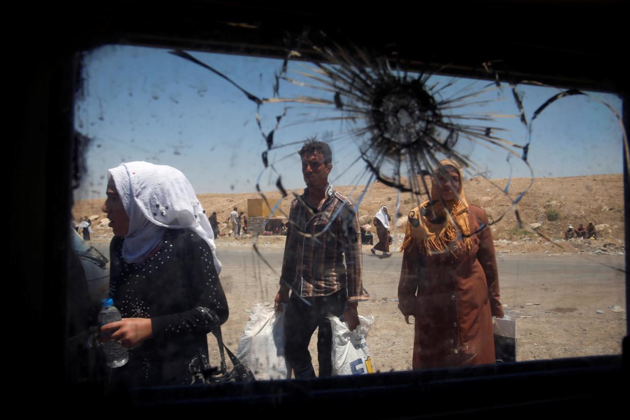 Displaced civilians move past the shattered glass window of an Iraqi forces armoured fighting vehicle in West Mosul, Iraq: Reuters