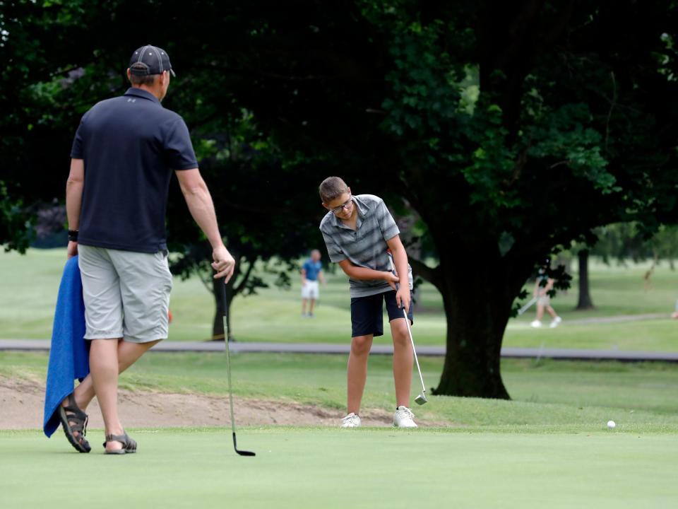 River View's Gavin Gress hits a putt under the watchful eye of his father and caddie, Chad Gress, during the first round of the 46th annual Zanesville District Golf Association Amateur tournament on Friday, June 24, 2023, at Hickory Flats Golf Course in West Lafayette, Ohio. Gress, in middle school, shot 70 and is one shot back of the lead.