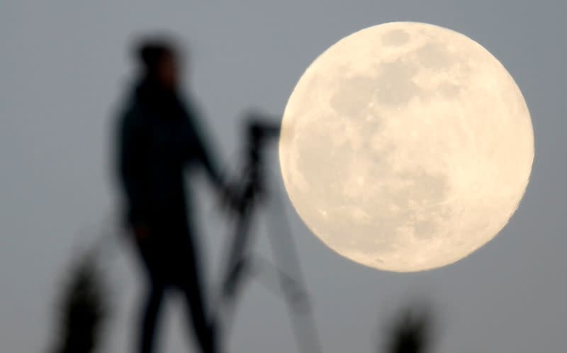 FILE PHOTO: A woman photographs the Pink Supermoon over mountain Smetovi, during an astronomical event that occurs when the moon is closest to the Earth in its orbit, making it appear much larger and brighter than usual, in Zenica