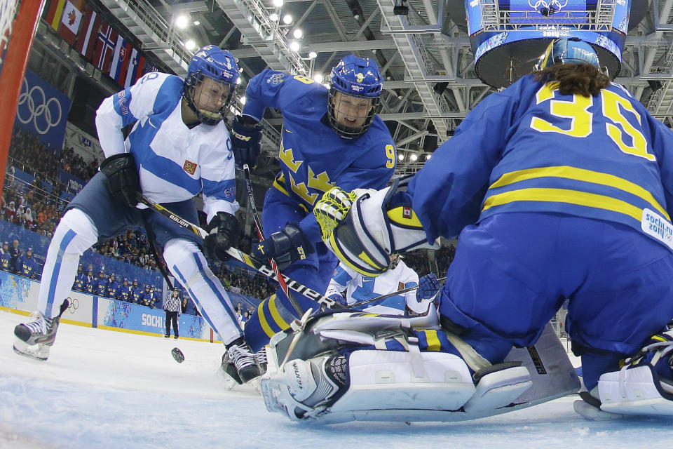 Venla Hovi of Finland, left, and Josefine Holmgren of Sweden, center, battle for control of the puck in front of Sweden's goalkeeper Valentina Wallner during the 2014 Winter Olympics women's ice hockey game at Shayba Arena, Saturday, Feb. 15, 2014, in Sochi, Russia. Sweden defeated Finland 4-2 in the quarterfinal game. (AP Photo/Brian Snyder, Pool)