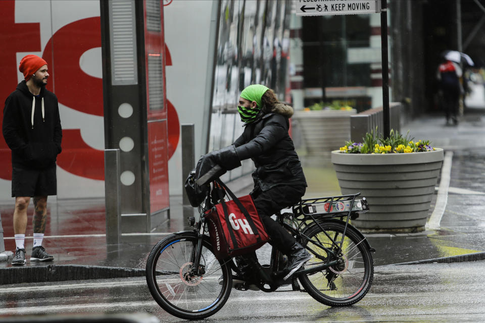 A delivery person with his face covered during the coronavirus outbreak turns onto Seventh Avenue Friday, April 3, 2020, in New York's Times Square. The new coronavirus causes mild or moderate symptoms for most people, but for some, especially older adults and people with existing health problems, it can cause more severe illness or death. (AP Photo/Frank Franklin II)