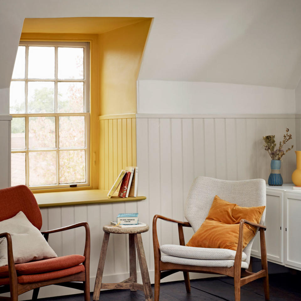 window frame painted yellow with two armchairs in front