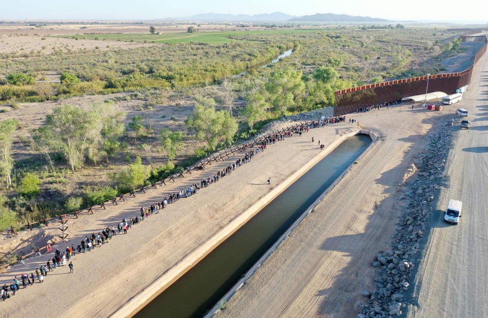 In an aerial view, immigrants seeking asylum in the United States wait in line near the border fence to be processed by U.S. Border Patrol agents after crossing into Arizona from Mexico in Yuma, Arizona, on May 11, 2023.<span class="copyright">Mario Tama—Getty Images</span>