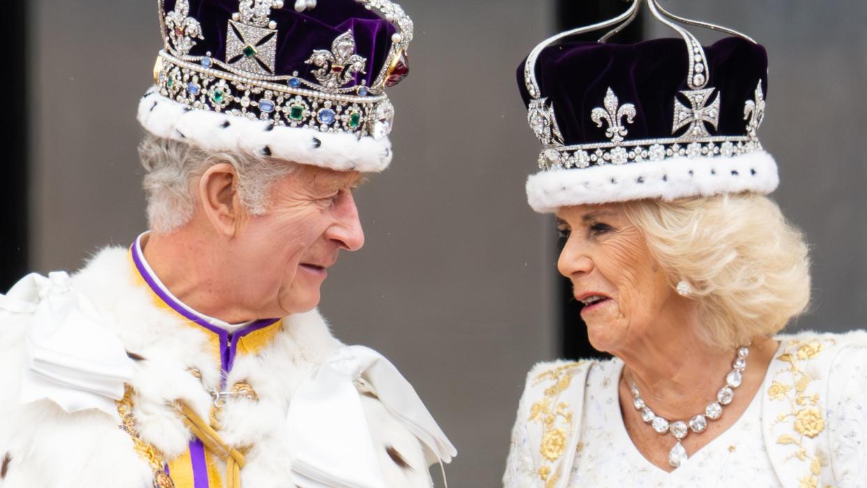 King Charles in his coronation robes talking to Queen Camilla