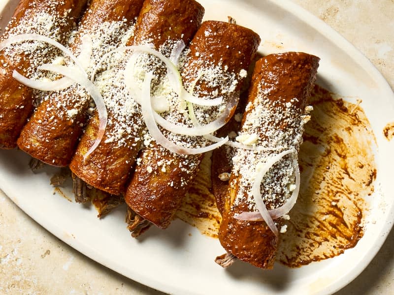 An overhead shot of Mexican beef enchiladas on a platter with some removed.